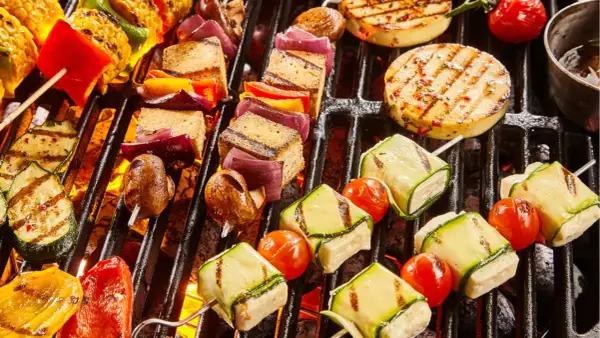 Bunte Spieße mit Tofu, Zucchini, Tomaten, Mais und Paprika brutzeln auf dem Grill. Ein Genuss für vegetarisches Grillen!