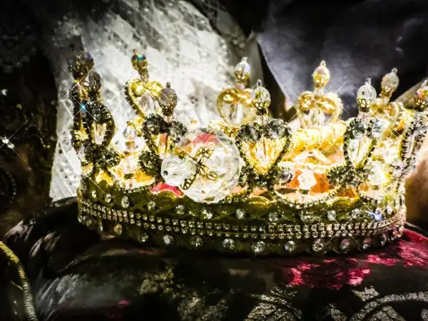 Korona zdobiona klejnotami, symbol bogactwa i władzy, przypomina o globalnym wydobyciu złota.