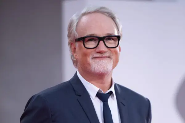 David Fincher, reżyser znany z mrocznych i wciągających filmów, w eleganckim garniturze i okularach.