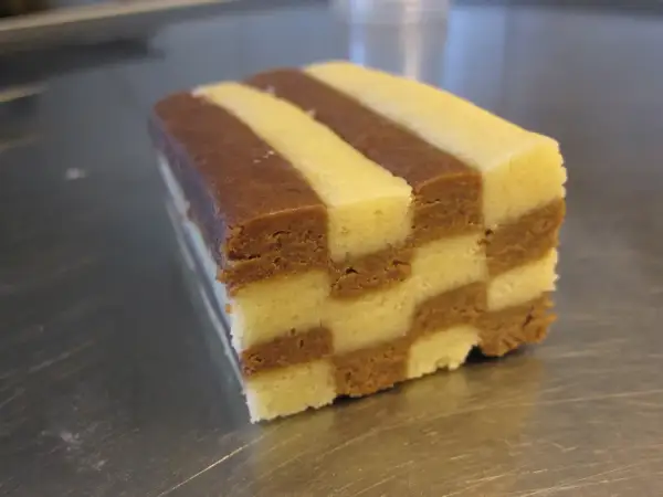 En bit av ett hembakat schackrutemönstrat kex med choklad och vaniljsmak.