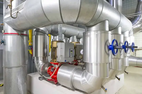 Detailaufnahme einer Anlage mit großen Rohren, Pumpen und Ventilen, die an ein mini blockheizkraftwerk angeschlossen sind.