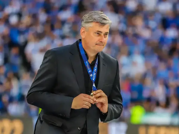 Maciej Skorża, po wygranej, trzyma medal. W tle tłum kibiców. Jego żona wspierała go w walce z chorobą.
