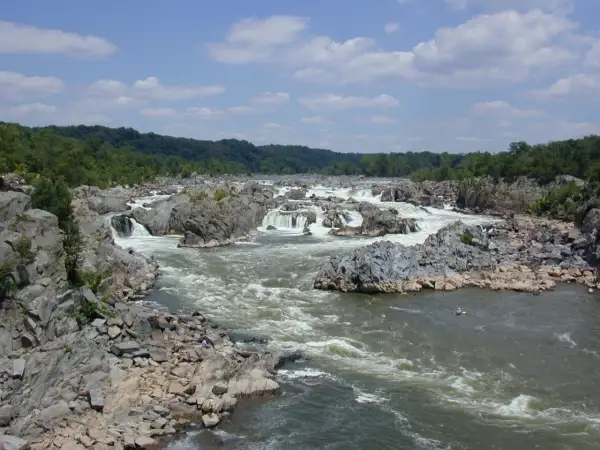 Potomac: bystrza i skały na rzece, zalesione brzegi w tle.