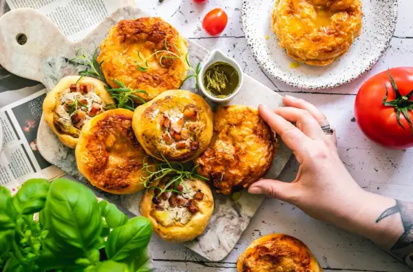 Mini tarty z boczkiem i serem, podane z oliwą z oliwek i ziołami. Zdrowe tłuszcze produkty na talerzu.