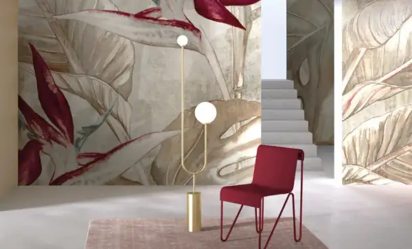Egzotyczne, drogie tapety z motywem liści i kwiatów tworzą luksusową atmosferę. Czerwone krzesło i złota lampa dodają elegancji.