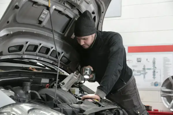 Mechanik z latarką bada silnik 1.9 TDI.