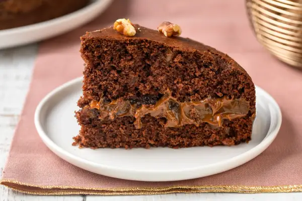 Una fetta di torta al cioccolato con ripieno di caramello e noci, perfetta tra i dolci per le feste.