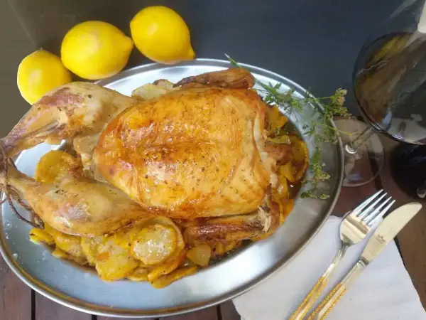 Un capón asado, jugoso y dorado, servido con patatas y limones. ¡Un festín para los sentidos!