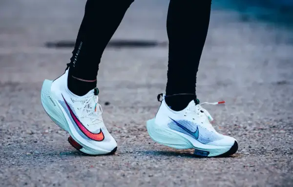 Course sur route avec des chaussures de running blanches dotées d'une plaque carbone.