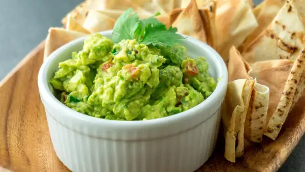 Pyszne guacamole z pomidorami i kolendrą, idealne do szybkiego przygotowania. Podane z chrupiącymi nachos.