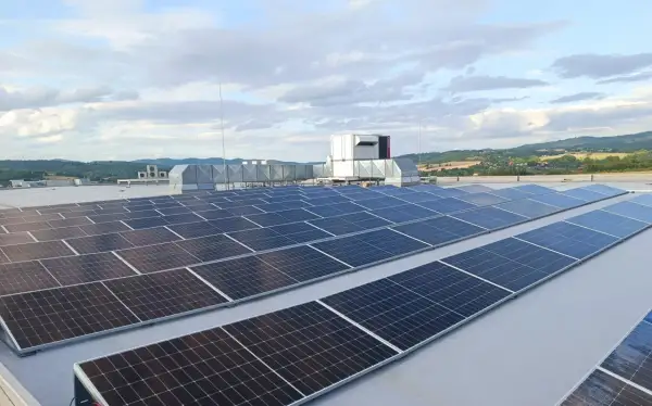 Duże panele fotowoltaiczne na dachu, obok systemów wentylacyjnych i agregatu prądotwórczego, zapewniające niezawodność energetyczną.