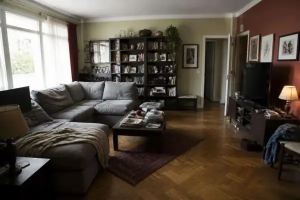 Soggiorno accogliente con divano angolare grigio, libreria piena e parquet. Idee originali per arredare soggiorno con stile.
