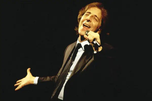 Giorgio Gaber canta con passione, la sua voce risuona come nei testi de "Il Conformista", un'icona della musica italiana.
