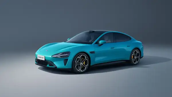 El elegante **Xiaomi SU7** azul turquesa, un sedán eléctrico con líneas aerodinámicas y techo negro, se exhibe sobre un fondo gris neutro.