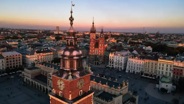 Zachód słońca nad Rynkiem Głównym w Krakowie. Widać wieżę Ratuszową i Kościół Mariacki, ikoniczne kraków zabytki.