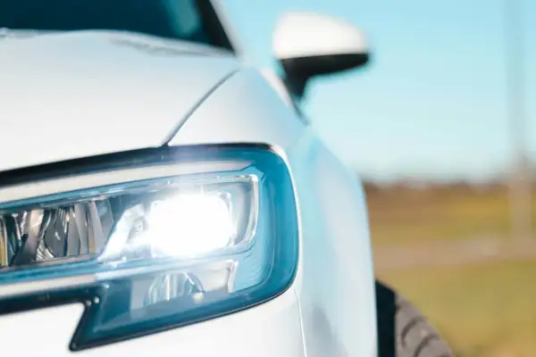 Biały Ford Transit z włączonymi światłami pozycyjnymi. Bezpieczniki świateł pozycyjnych są kluczowe dla sprawnego działania oświetlenia.