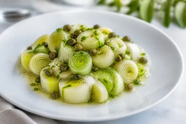 Poireaux vinaigrette, coupés en tronçons, nappés d'une sauce légère et parsemés de câpres. Un plat frais et savoureux.
