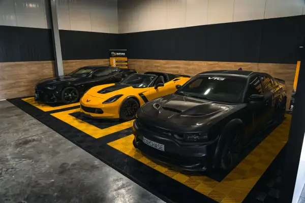 Trzy potężne amerykańskie marki samochodów: czarny Chevrolet Camaro, żółty Chevrolet Corvette i czarny Dodge Charger.
