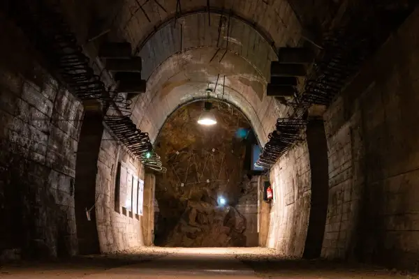 Wnętrze tunelu w Górach Sowich. Betonowe ściany, łukowe sklepienie i oświetlenie tworzą mroczny klimat.