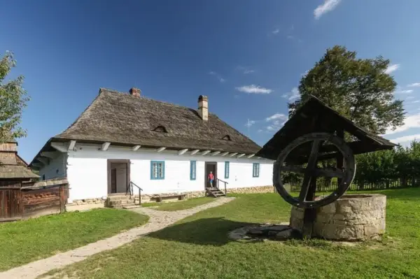 Skansen Sanok: tradycyjna chata i studnia. Idealne miejsce na letnie imprezy i spacery po historii.