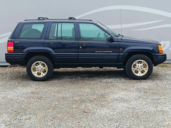 Granatowy Jeep Grand Cherokee ZJ z lat 90. na złotych felgach, gotowy na przygodę.