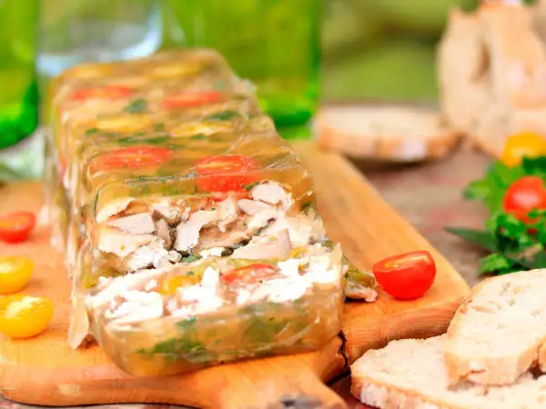 Un appétissant lapin en gelée, garni de tomates cerises et d'herbes, prêt à être dégusté avec du pain frais.
