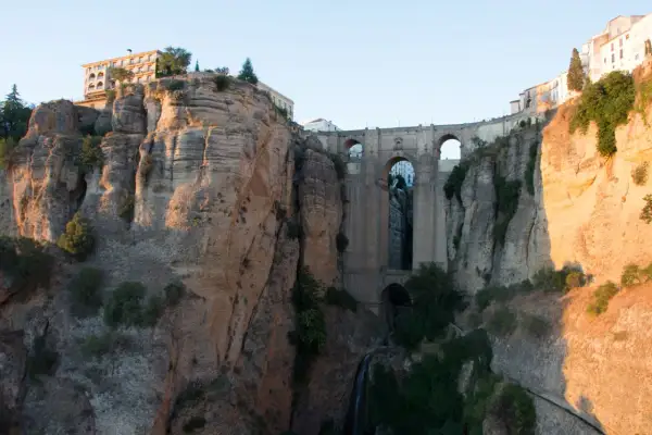 Impresionante puente de piedra sobre un profundo tajo, ideal para rutas por Ronda. Edificios se asoman al abismo.