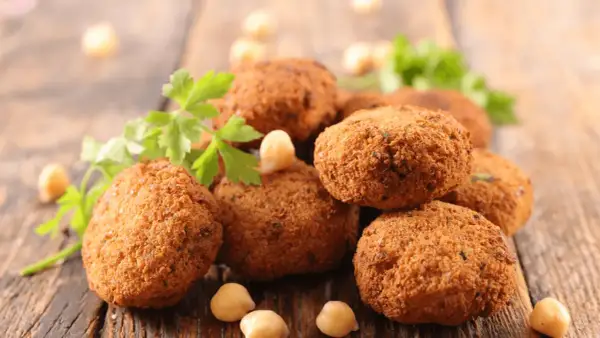 Polpette dorate e croccanti, perfette polpette senza uova, guarnite con prezzemolo fresco e ceci su un tagliere di legno.