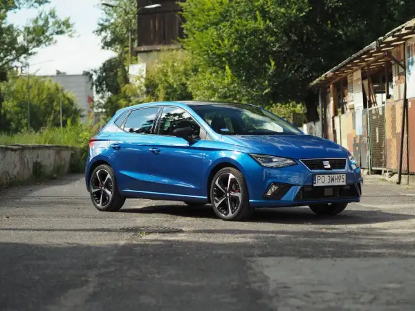 Niebieski Seat Ibiza na tle zieleni i budynków. Poznaj jego seat ibiza dane techniczne.