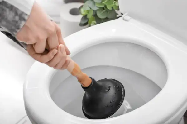 Hand mit Saugglocke versucht, eine verstopfte Toilette zu befreien.