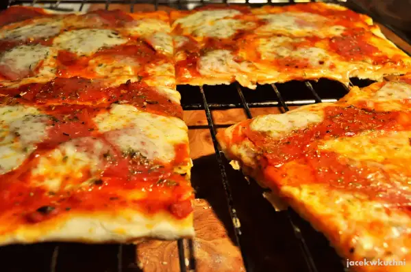 Pyszna pizza na cienkim cieście, z ciągnącym się serem i aromatycznym sosem pomidorowym, prosto z pieca.