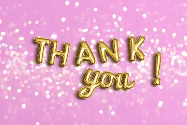 Globos dorados forman "THANK YOU" sobre fondo rosa con luces bokeh. Perfectas frases de agradecimiento para cualquier ocasión.