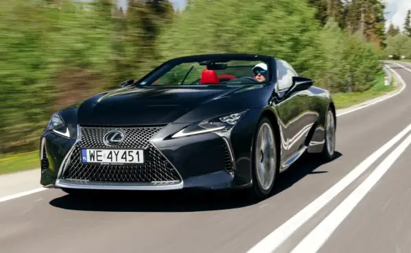 Czarny kabriolet Lexus LC 500 z czerwonym wnętrzem sunie po krętej drodze, zapewniając czystą przyjemność z jazdy i poczucie lexus relax.