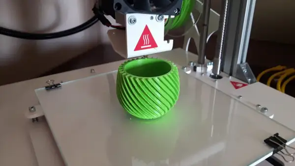 Drukarka 3D drukuje zielony, spiralny wazon.