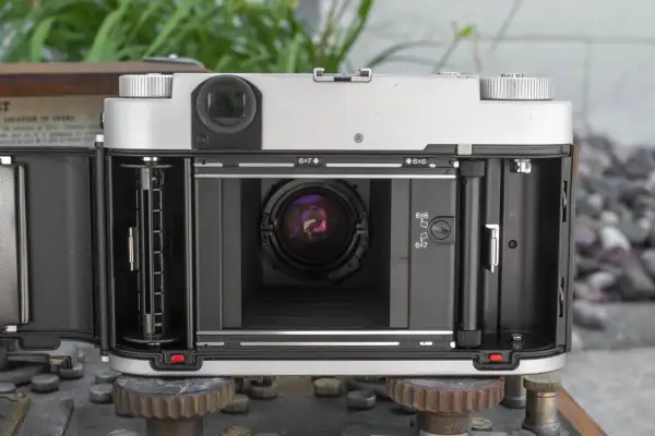 The open back of a Fuji GF670W medium format camera, revealing the film path and lens.