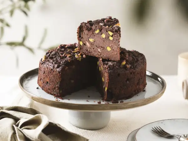 Torta di pane al cioccolato, ricca e golosa, con pistacchi e cacao, servita su un'alzata.