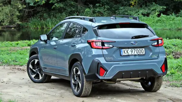 Szary Subaru Crosstrek 2025 na tle zieleni i wody. Gotowy na przygodę!