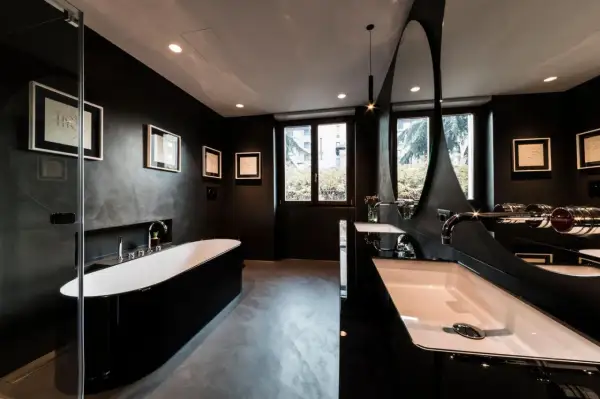 Elegantes, dunkles Badezimmer mit freistehender schwarzer Wanne, Doppelwaschbecken und moderner Spiegelarchitektur.
