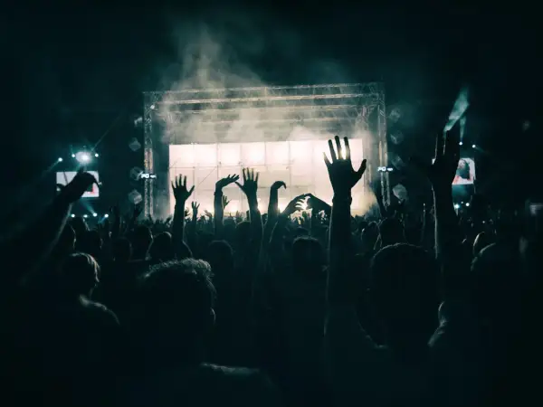 Folla in estasi al ritmo del dj techno berlino, mani alzate verso il palco illuminato.