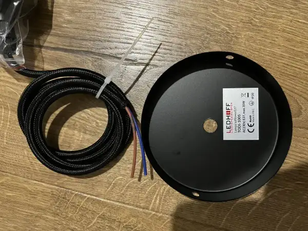 Czarny, pleciony kabel z kolorowymi żyłkami obok czarnej rozety sufitowej LEDHOFF.