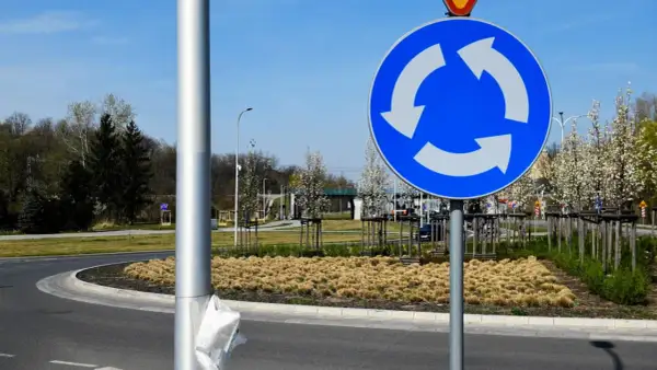 Znak informuje, kto ma pierwszeństwo na rondzie. Trzy białe strzałki na niebieskim tle wskazują kierunek ruchu i sugerują, że pojazdy na rondzie mają pierwszeństwo.