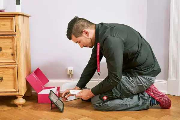 Technik sprawdza instrukcję na tablecie, przygotowując się do instalacji światłowodu. Dowiedz się, ile kosztuje podłączenie światłowodu.