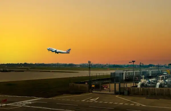 Flugzeug steigt auf vor orangefarbenem Himmel am internationalen Flughafen von London.