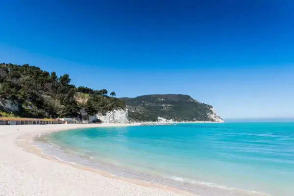 Spiagge di San Benedetto del Tronto con scogliere bianche, vegetazione lussureggiante e mare cristallino sotto un cielo azzurro.