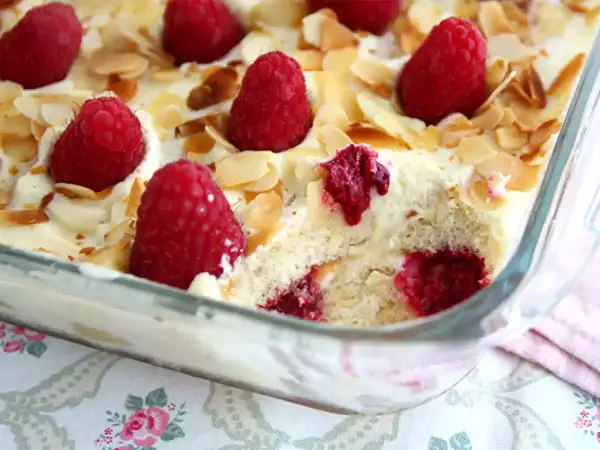 Un délicieux tiramisu framboise, garni de fruits rouges frais et d'amandes effilées, prêt à être dégusté.