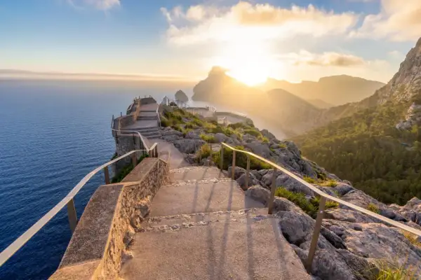 Sonnenuntergang über dem Meer, ein Pfad mit Treppen führt zu Aussichtspunkten. Perfekte Reiseziele im Februar für atemberaubende Ausblicke.