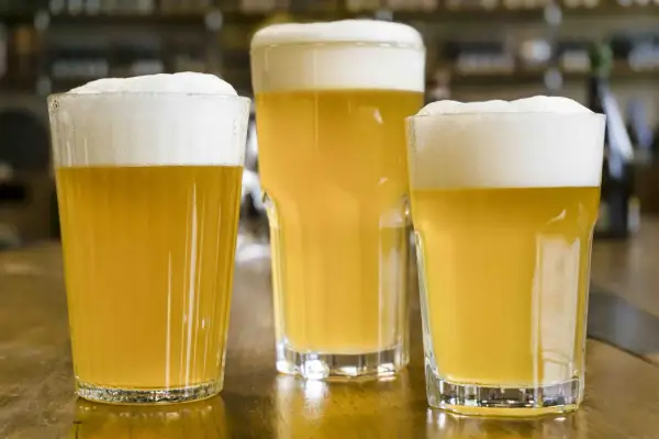 Tre bicchieri di birra blanche con schiuma abbondante. Le birre hanno un colore dorato chiaro, tipico delle birre blanche, e le loro caratteristiche fresche e dissetanti sono evidenti.