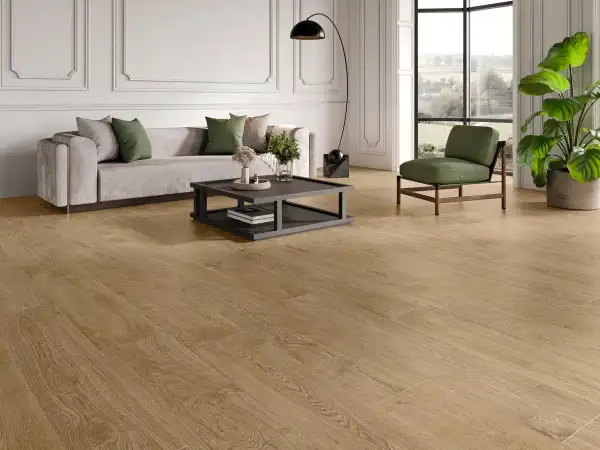 Elegante salón con sofá gris, mesa de centro y sillón verde, sobre un cálido pavimento SPC de madera.