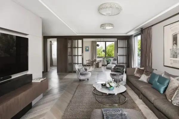Elegancki salon z kanapą, fotelami i stolikiem kawowym. W tle widać jadalnię i okno z widokiem na zieleń. Całość emanuje wyrafinowanym, **włoskim stylem**.