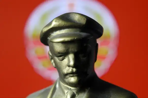 Popiersie mężczyzny w czapce na tle czerwono-białego okręgu.